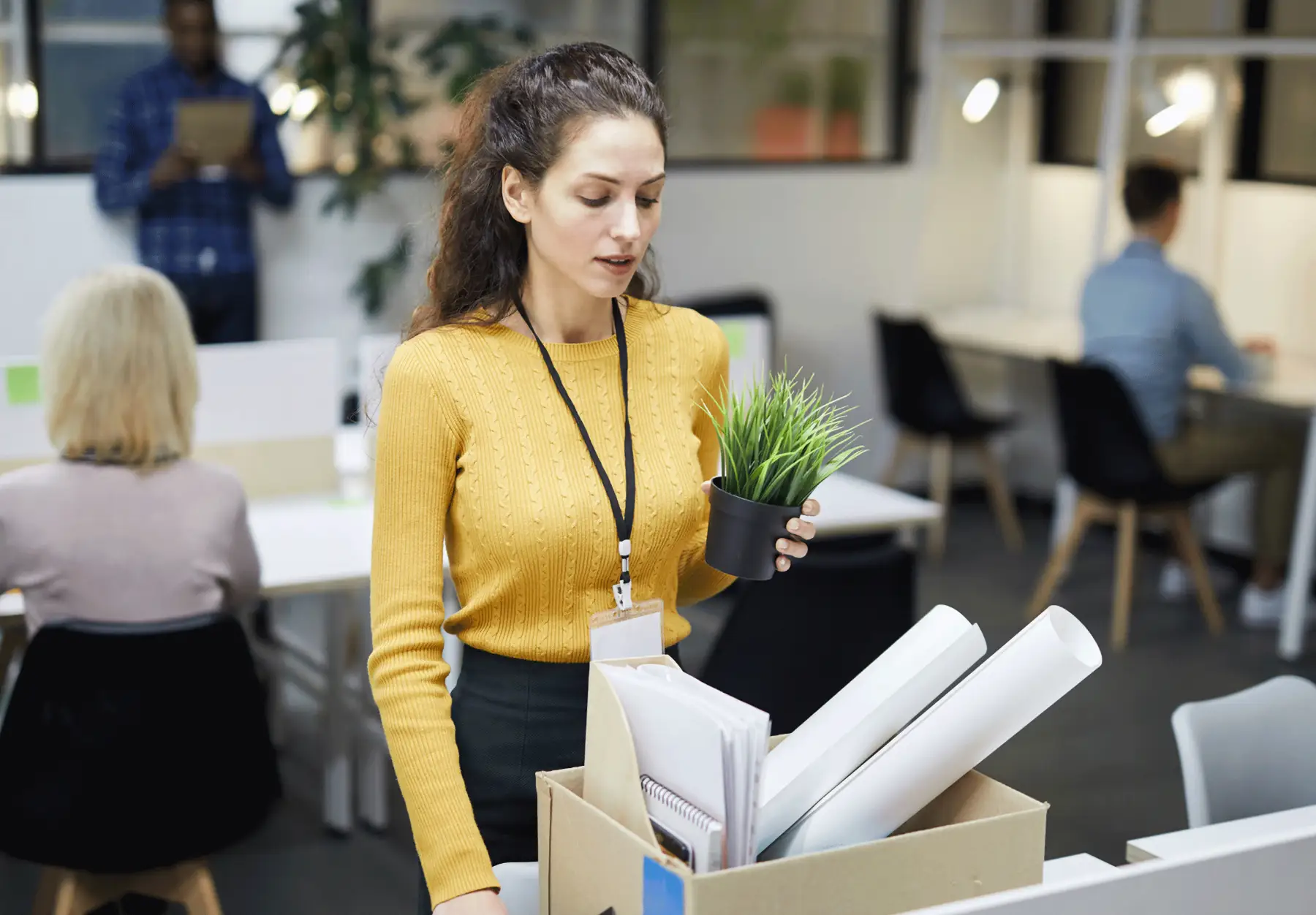worker puts an office plant into a box of papers